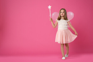 Cute little girl in fairy costume with wings and magic wand on pink background. Space for text