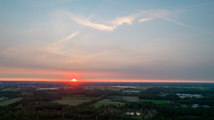 Aerial view of a beautiful and dramatic sunset over a forest lake reflected in the water, landscape drone shot. Blakheide, Beerse, Belgium. High quality photo