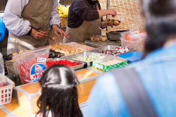 夏祭りの屋台でたこ焼きを買っている女の子と母親の親子