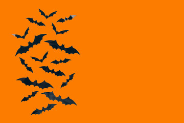 Halloween background - decorative paper bats on orange background with copy space. Halloween decorations or party invitation concept. Selective focus