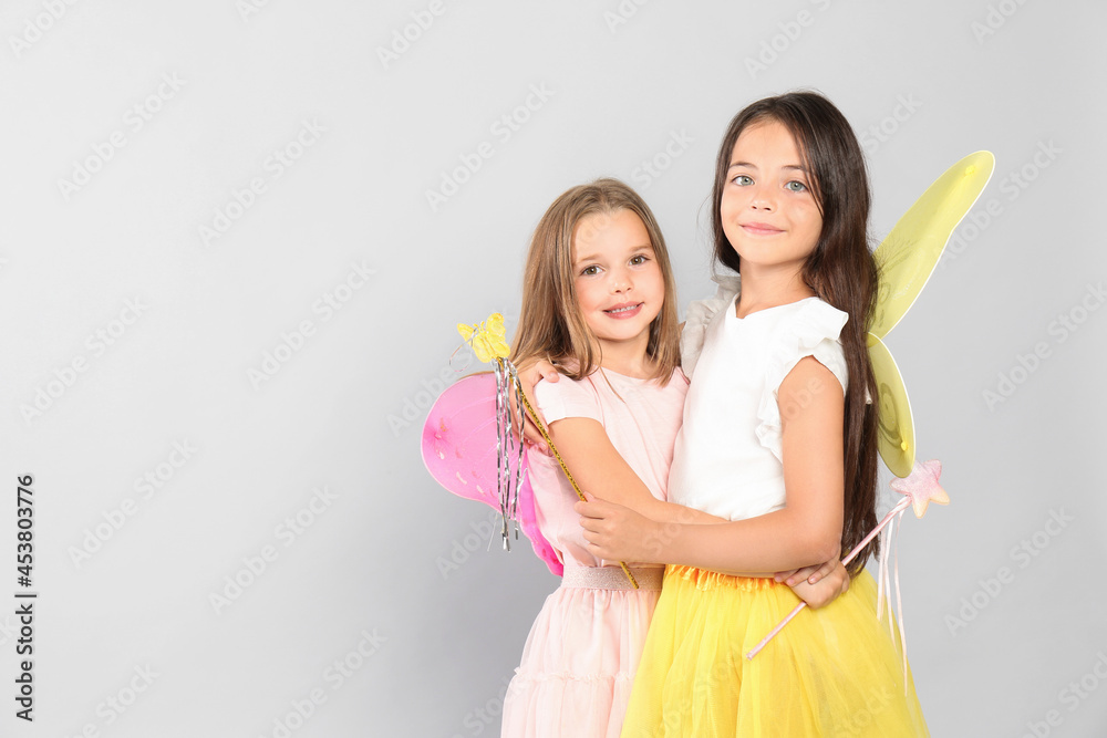 Canvas Prints cute little girls in fairy costumes with wings and magic wand on light background. space for text