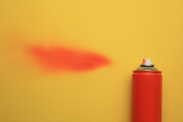 Can of red graffiti paint and sprayed dye sample on yellow background, top view
