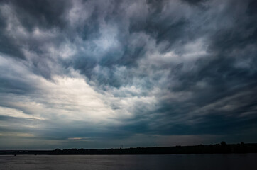 Fototapeta na wymiar Dramatic beautiful stormy sky over the lake. Large gray rain and motley cloud above the horizon