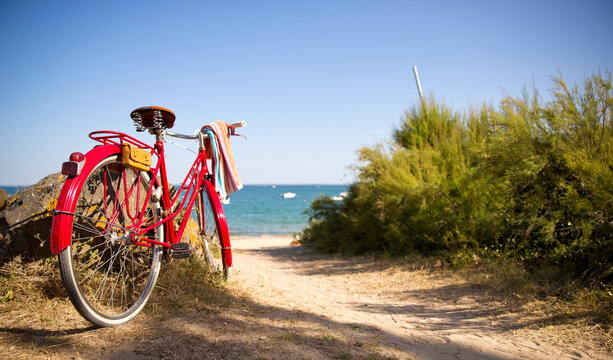 Vieux vélo rouge au bord de la plage et de la mer bleu.