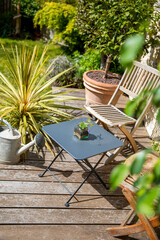 Petit jardin en terrasse en bois, chaise et plante au soleil.