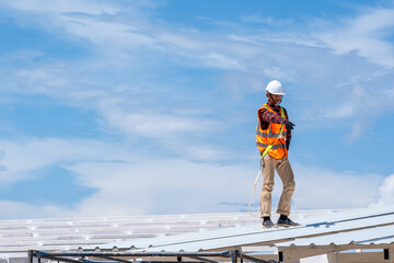 Worker with roofer tools wearing protective gear installing new roof on top roof at construction site,metal roof.