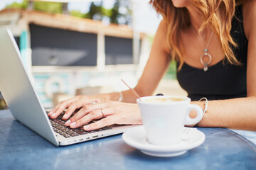 Unrecognizable spanish woman writing on laptop and having coffee