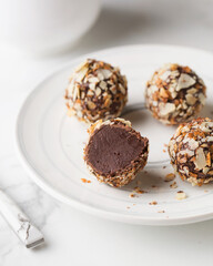 Chocolate candies. Delicious dessert on a light background. Truffles with waffle crumbs. Sweets on a white plate. Macro photography of sweets. Candy Cut