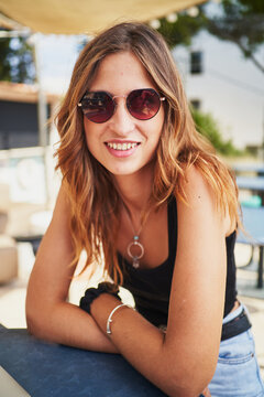 Young spanish woman with sunglasses smiling at camera on a cafe