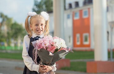 little funny schoolgirl with bouquet go to school in sunny day