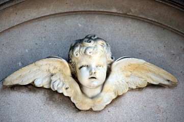 An old, weathered sandstone sculpture of an angel with spread wings.