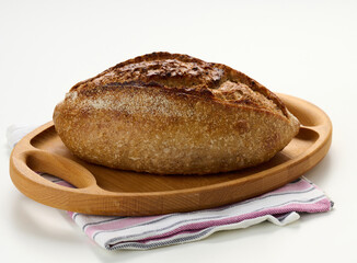 oblong baked bread made from white wheat flour on a white table, crispy bun