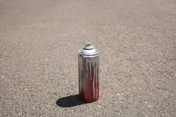 Used can of spray paint on asphalt road, space for text. Graffiti supplies