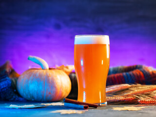Close-up of a glass of craft pumpkin ale on a neon background . Seasonal traditional beer for...