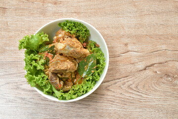 spicy fried pork bone with coconut milk curry on lettuce in bowl