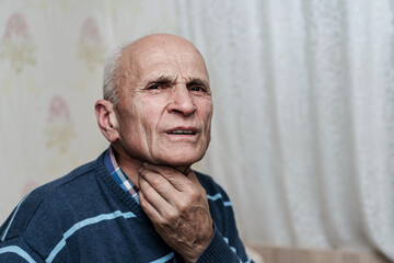 Old pensioner man holding throat with hand and has face with pain grimace.