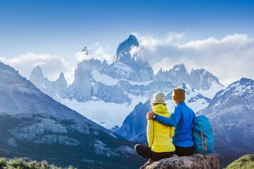 Travelers couple in love enjoying the view of majestic Mount Fitz Roy - symbol of Patagonia, Argentina
