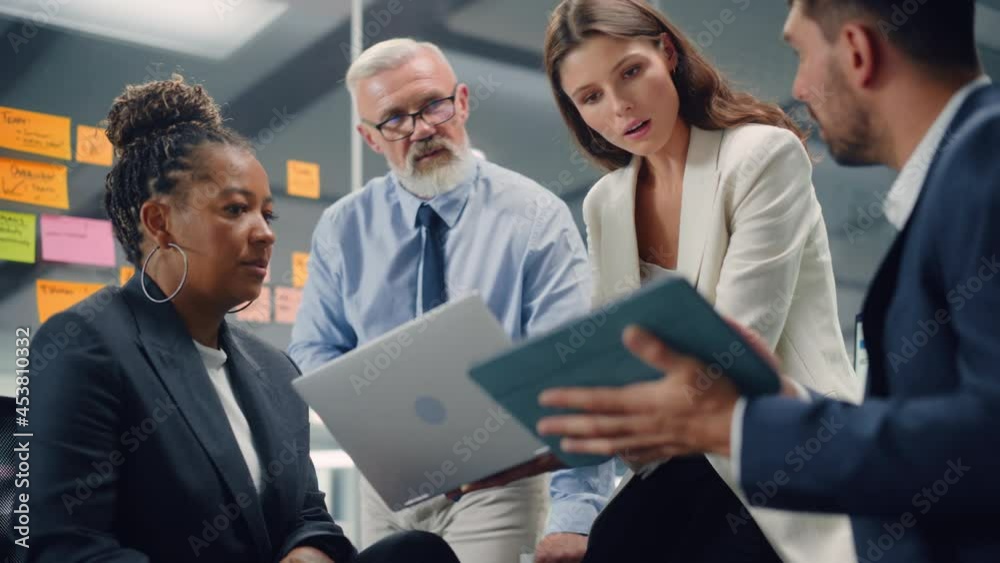 Aufkleber in modern office: diverse team of managers use laptop and tablet computers at a company meeting disc
