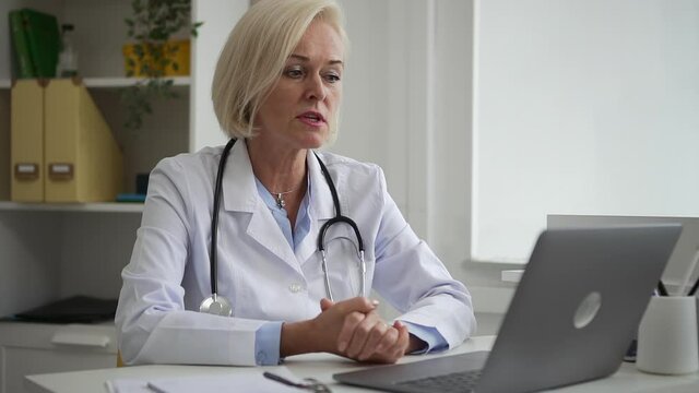 Doctor distance appointment internet resources. Spbd Mature female family physician with stethoscope gives recommendations to patient at videochat in clinic