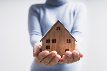 Close up hand of woman holding model house, have home and happy family and real estate concept