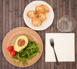 half an avocado, arugula and cherry tomatoes on plate