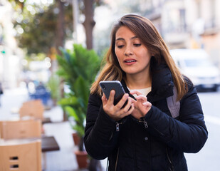 Young woman traveler consulting navigation app in cellphone