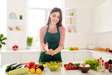 Obraz na płótnie Canvas Photo of pretty happy positive young woman hold salt make salad health food wear apron indoors inside kitchen