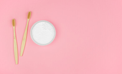 Environmentally friendly personal hygiene products. Wooden toothbrushes and tooth powder on a pink background. Oral cavity care.
