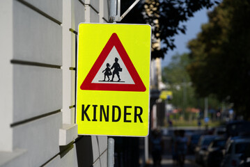 Warning traffic sign with illustration of school children and text Kinder (German, children) at City of Bregenz on a sunny summer Sunday. Photo taken August 15th, 2021, Bregenz, Austria.