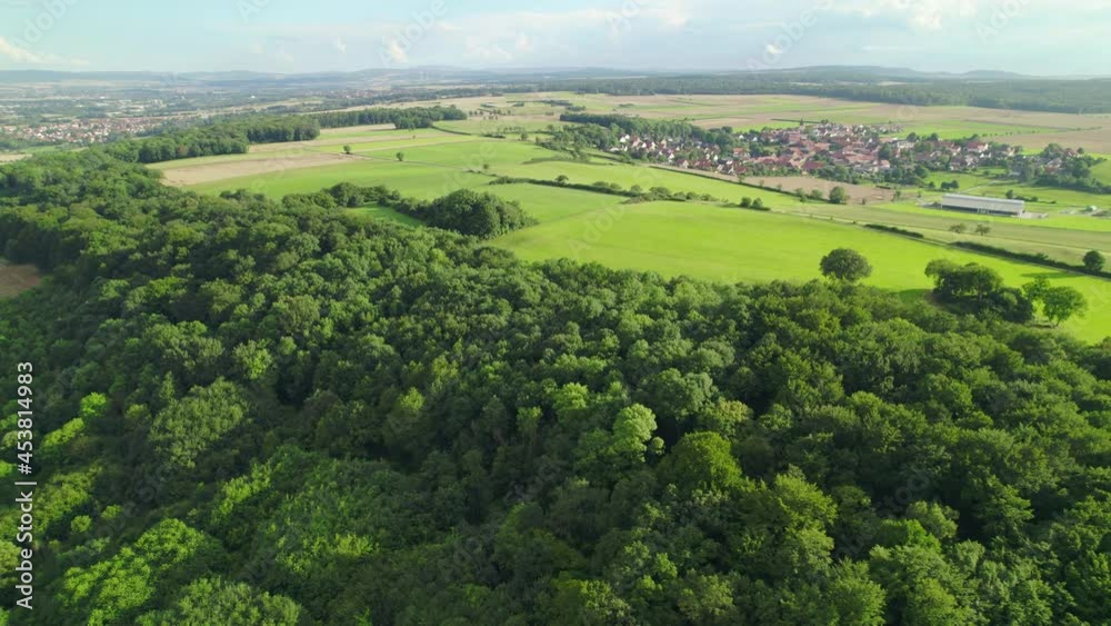 Sticker Aerial view of a German village surrounded by meadows, farmland and forest. A circular moving drone shot towards the town. Middle German Countryside.