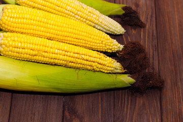 Sweet yellow corn lies on a wooden table.