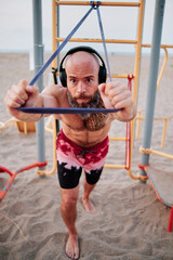 Fitness man doing calisthenics workout with a resistance rubber band.