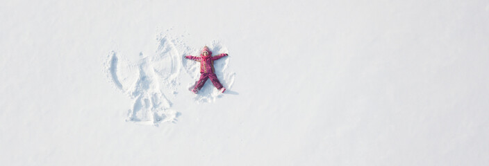 Child girl playing and making a snow angel in the snow. Top flat overhead view - 453818709