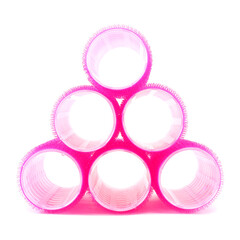Pyramid made of pink hair curlers on white background