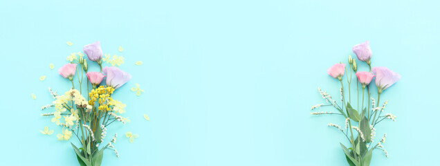 Top view image of pink, yellow and purple flowers composition over pastel blue background .Flat lay