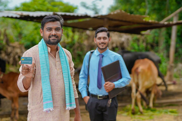 Young indian farmer showing card with bank officer