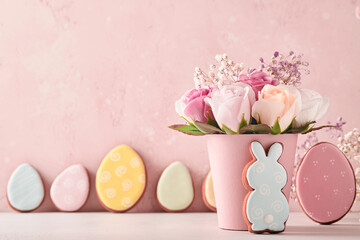 Easter background decoration with beautiful bouquet pink roses flowers in vase, Easter eggs, bunny and chick on pink background table. Easter concept with copy space.