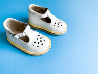 Children's shoes, the concept of the first step. Baby white on a blue colored background. Space for the text. The first steps of the baby. Children's background. Orthopedics. Top view, layout