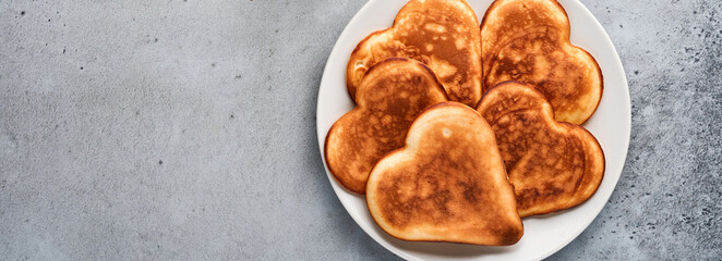 Pancakes in shape of breakfast hearts with chocolate sauce in gray ceramic plate cup of coffee on gray concrete background. Table setting for your favorite Valentines Day breakfast Top view copy space