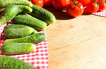 Red tomatoes and green cucumbers on a wooden background.Fresh vegetables top view with copy space for text. Flat lay. The concept of the harvest, vegetable garden.Natural products, agriculture. Layout