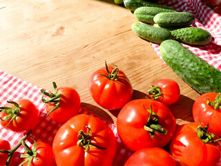 Red tomatoes and green cucumbers on a wooden background.Fresh vegetables top view with copy space for text. Flat lay. The concept of the harvest, vegetable garden.Natural products, agriculture. Layout