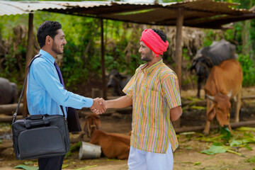 Young indian agronomist or officer visiting to farmer at his farm.