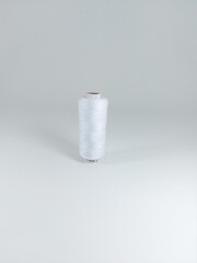 A spool of white thread with a white background. Idea for designing.