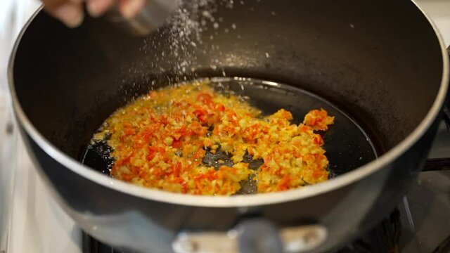 Ingredients being saut&eacute;ed in a skillet with salt - slow motion
