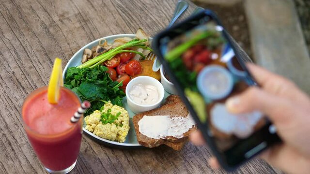 Top view of human hands taking pictures of a healthy plant based brunch with a smartphone