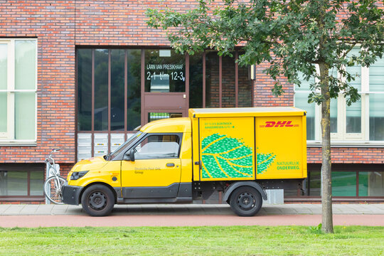 Electric DHL postal courier car in front of an apartment building in Arnhem, The Netherlands on August 3, 2021