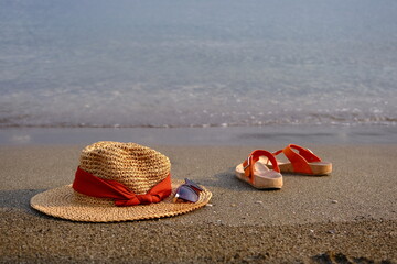Straw hat, sun glasses and slippers on the beach. Summer holiday concept.