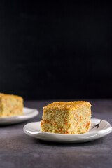 Close up square cut of homemade sweet and solf carrot cake on white plate on table. Delicious and healthy bakery.