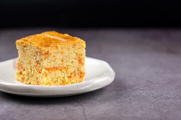 Close up square cut of homemade sweet and solf carrot cake on white plate on table. Delicious and healthy bakery.