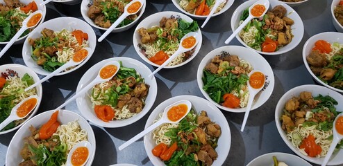 Noodle with chicken in white bowl being served in a row with chicken strip, vegetable, chili sauce. Mie Ayam Indonesia Traditional Noodle